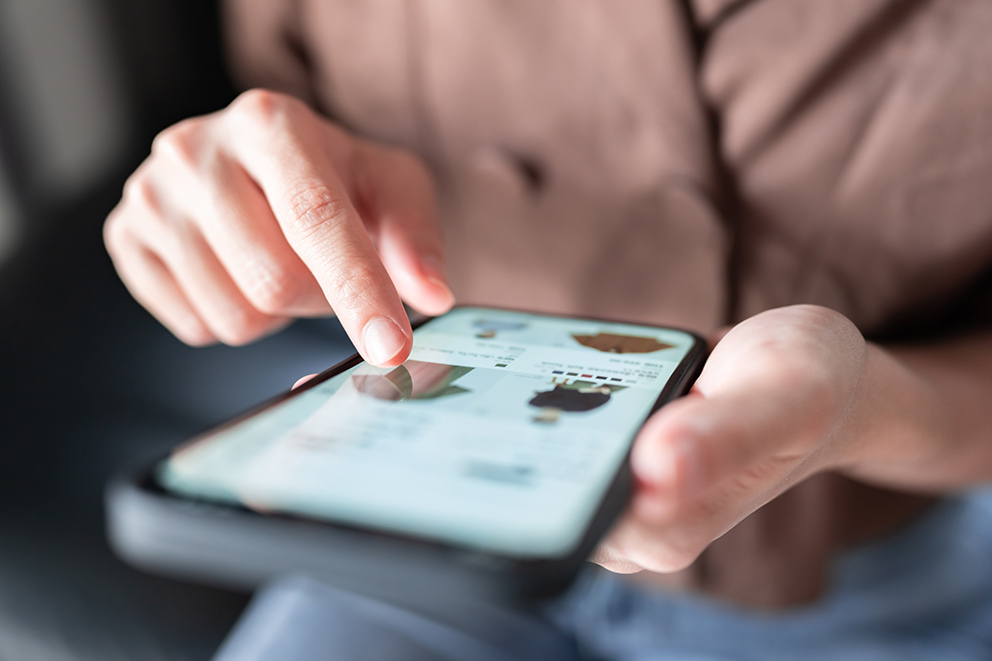 Hände tippen auf einem Smartphone mit geöffneter Shopping-App – Symbolbild für Social Commerce