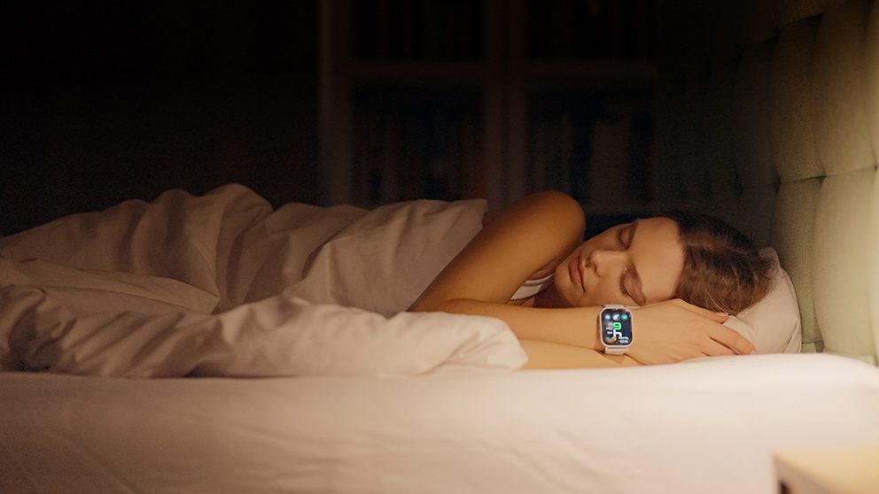Eine schlafende junge Frau, die eine Smartwatch trägt, um mittels Schlaftracking ihren Gesundheistzustand zu erfassen