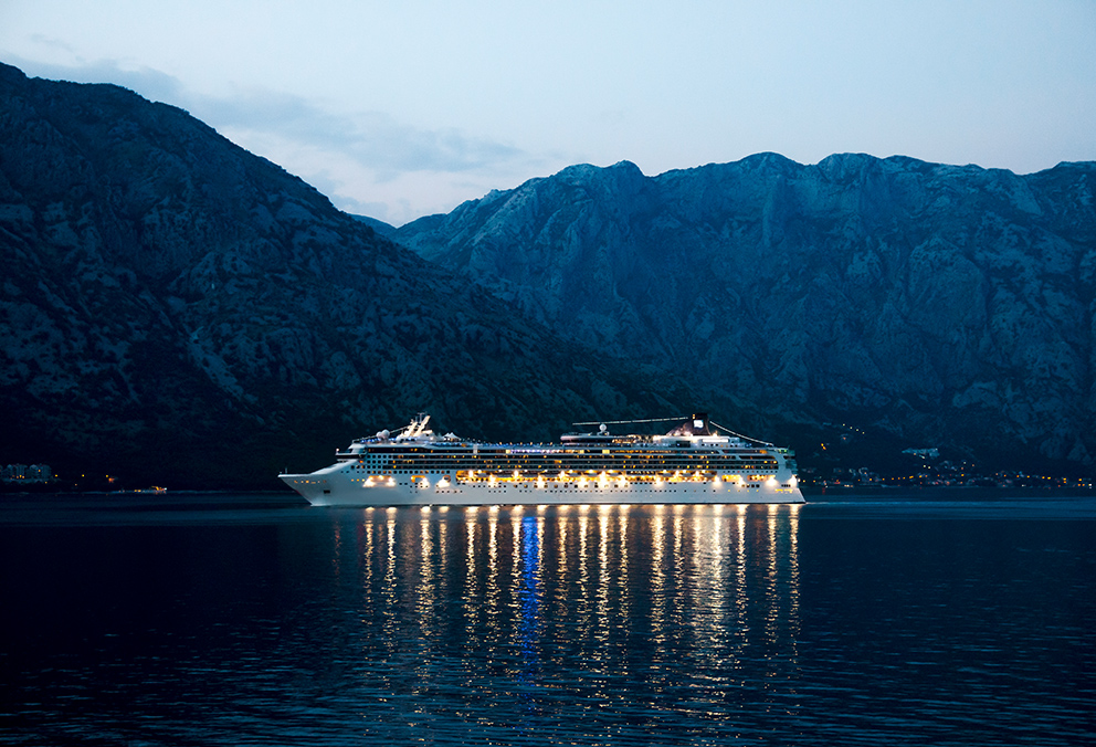 Ein Schiff auf See während der Abenddämmerung. Die Schiffsbeleuchtung ist dadurch gut zu erkennen.