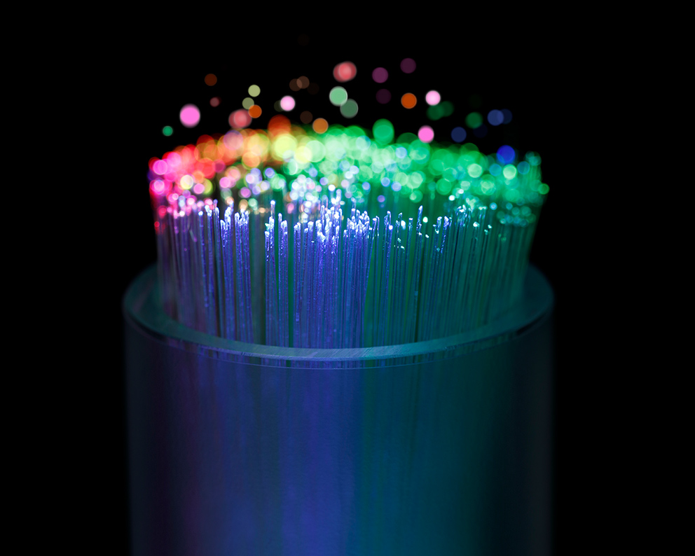 Eine Nahaufnahme eines Glasfaserkabels, dessen Kabel bunt erleuchtet sind, als Symbolbild für das Thema industrielle KI