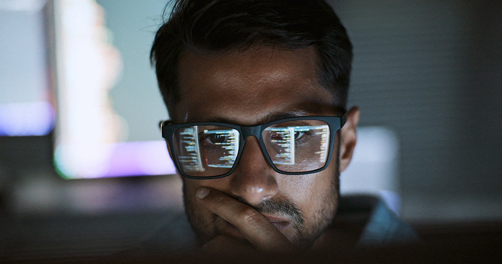 Nahaufnahme einer Person, die eine Brille trägt, in dessen Gläsern sich Datensätze von einem Bildschirm spiegeln, als Symbol für das Thema KI im Mittelstand