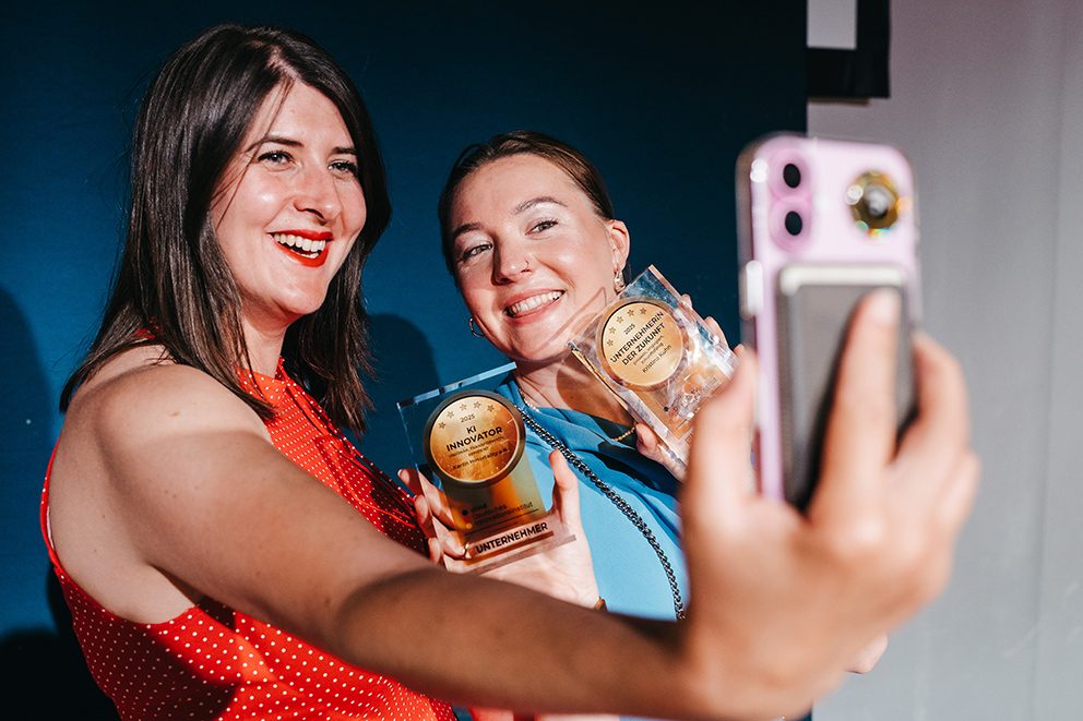 Zwei Frauen, die ein Selfie mit ihrer Unternehmensauszeichnung machen
