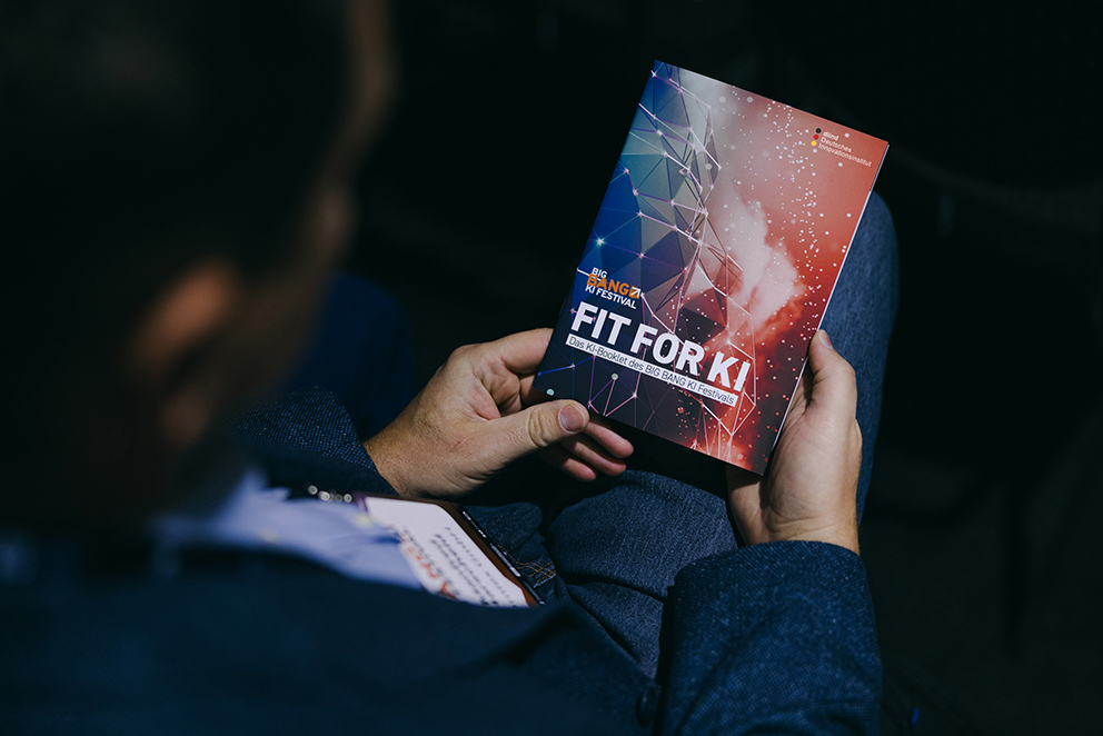 Eine Person, die das Programm des Fit for KI-Zertifikats in den Händen hält