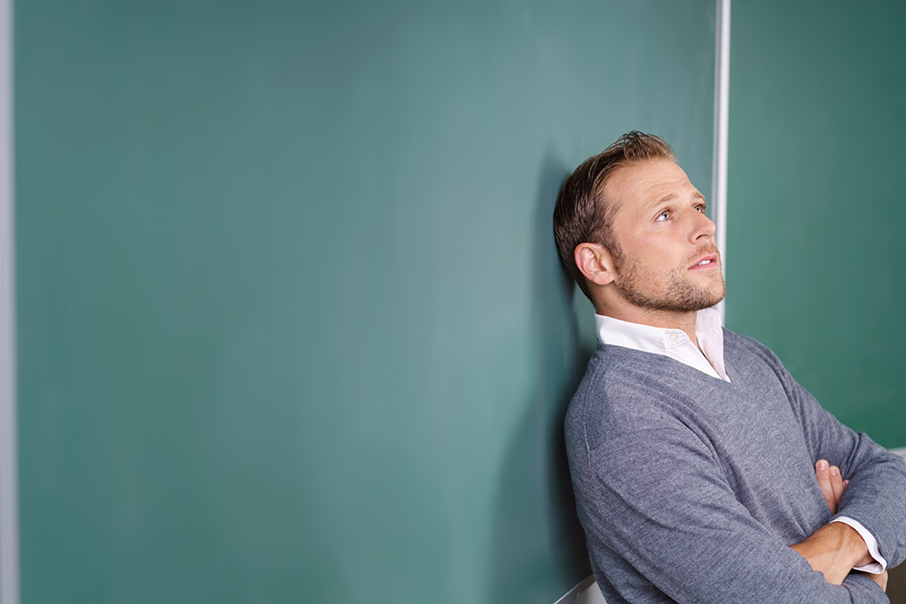 Ein Mann lehnt an einer Wand und guckt nach oben, als Symbol für das Thema Mentale Gesundheit am Arbeitsplatz